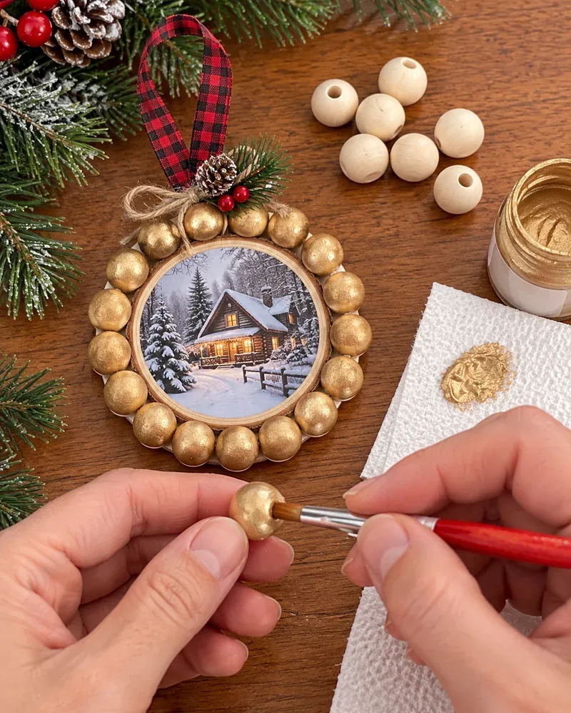 DIY picture frame Christmas ornament: a round wood photo ornament edged with wood beads being painted gold