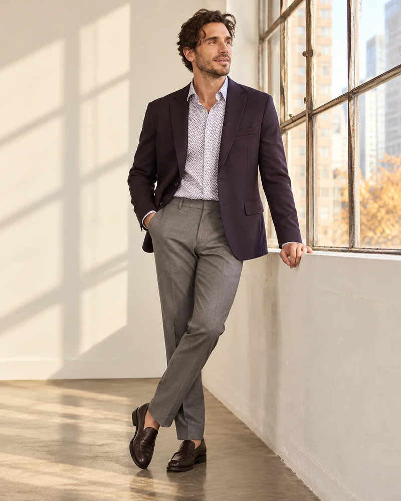 Man in a dark plum blazer, open-collar shirt and gray trousers, a smart casual Thanksgiving dress for men