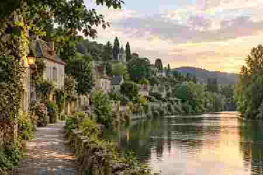 River town video frame with blocky compression artifacts: square macroblocks in the sky, trees and water