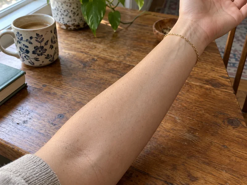 Drag to compare a bare forearm with the same arm wearing a fine-line botanical tattoo (before)