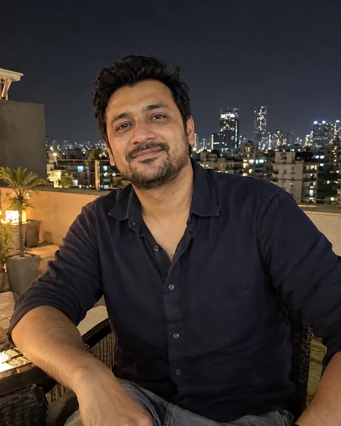 Natural dating photo of a man on a rooftop at night with city lights