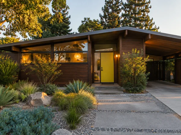 Mid-century modern bungalow with wood siding and a yellow door