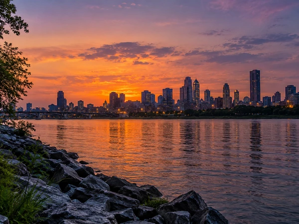 City skyline silhouette at dusk with lights spreading below