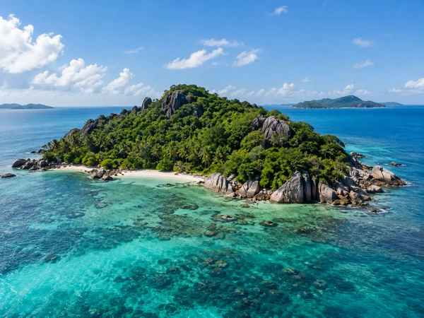 Lush green tropical island with rocky cliffs in clear blue water