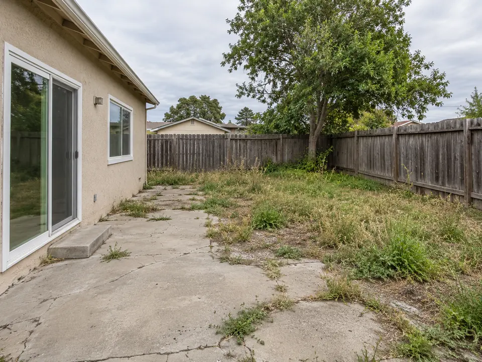 Drag to compare an overgrown backyard and the same yard as a modern patio (before)