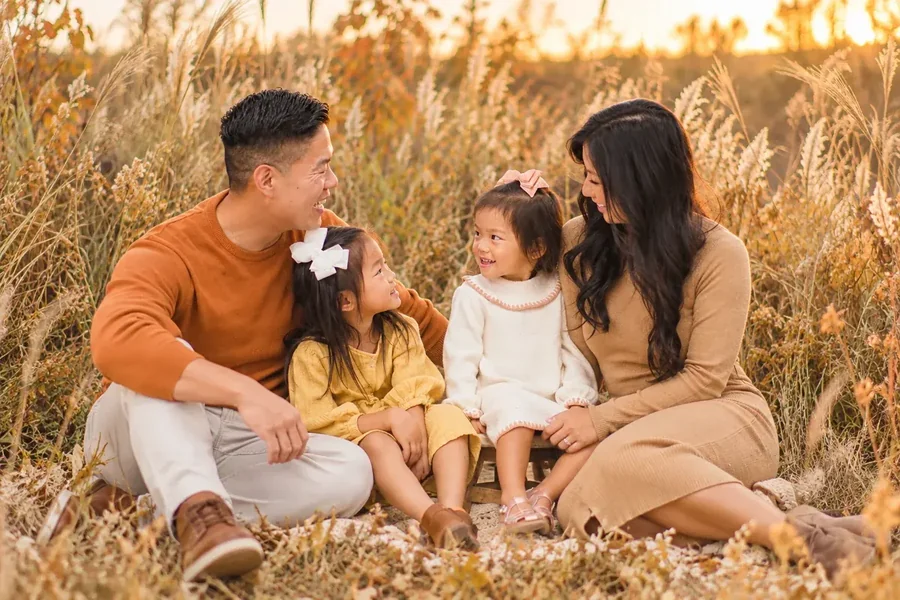 A family in coordinated fall colors sitting together in a golden field