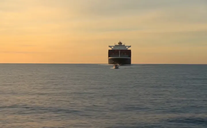 Frame from the extended part of the clip: a large ship approaching on a calm sea at sunset