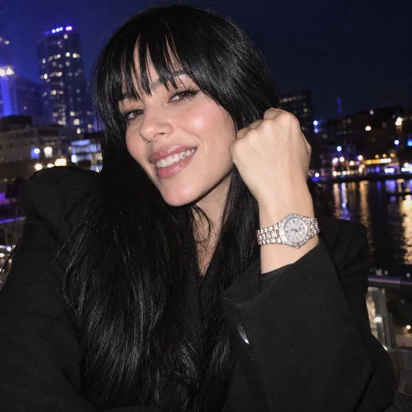 Woman with bangs smiling with diamond grillz and a fist showing an iced-out watch