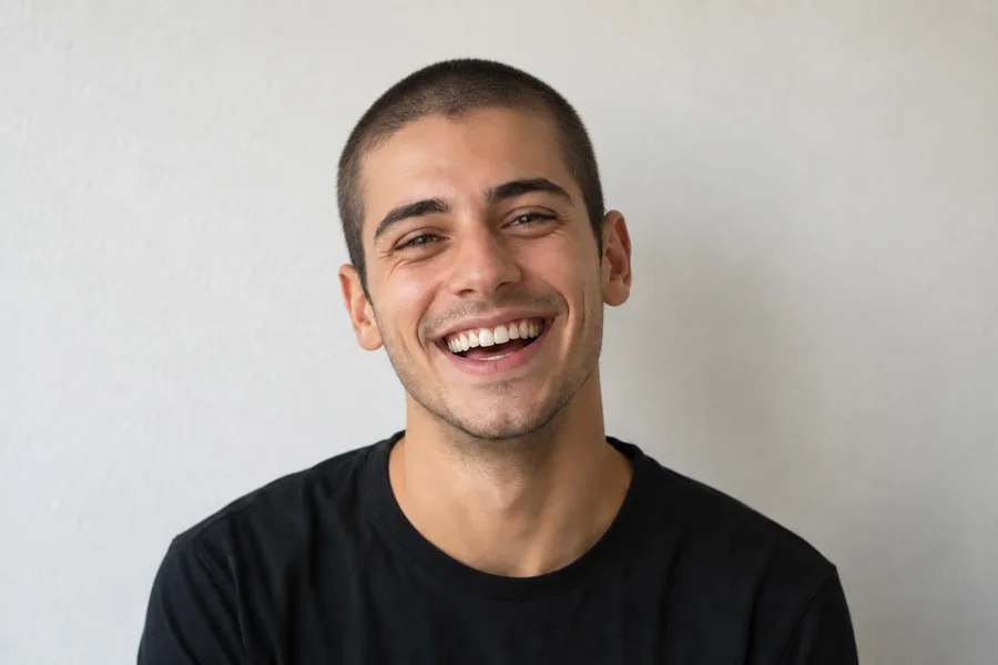 Drag to compare the smiling portrait before and after the buzz cut filter (after)