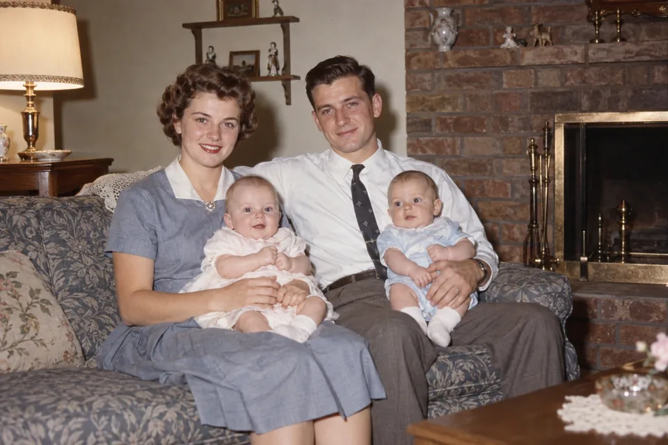 Drag to compare the black and white 1950s family on a sofa and the colorized photo (after)