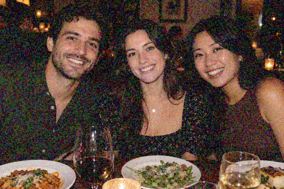 Drag to compare the grainy candlelit dinner photo of three friends and the denoised photo (before)