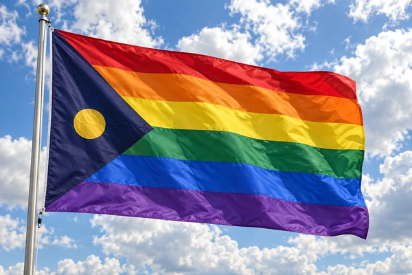 Rainbow pride flag with a dark triangle at the hoist waving in the clouds