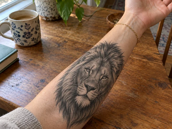Realistic lion tattoo on an outer forearm