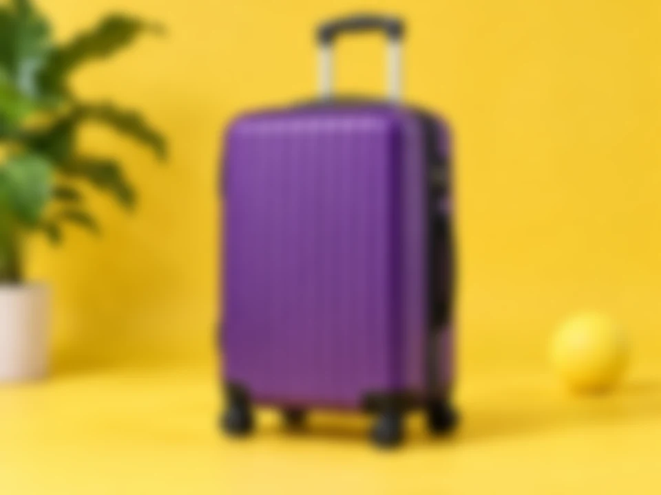 Drag to compare the blurry product photo of a purple suitcase and the sharp version (before)