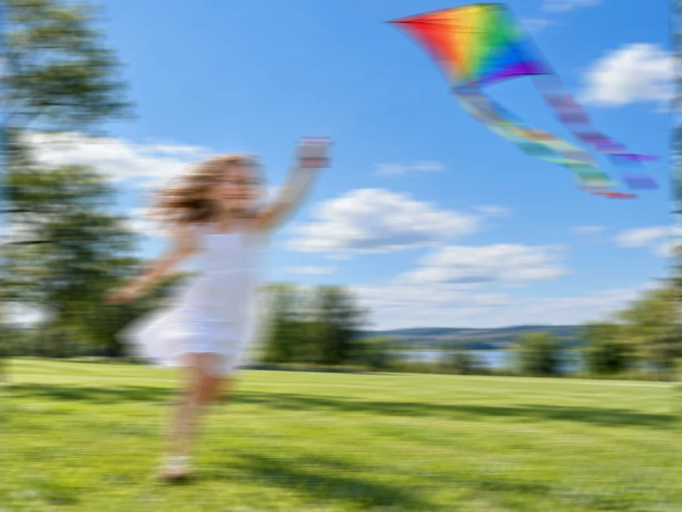 Drag to compare the motion-blurred photo of a girl flying a kite and the clear image (before)