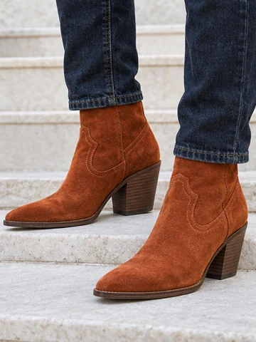 Burnt orange suede western ankle boots worn on a white step
