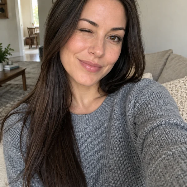 Woman in a grey sweater giving a cheeky wink in a selfie